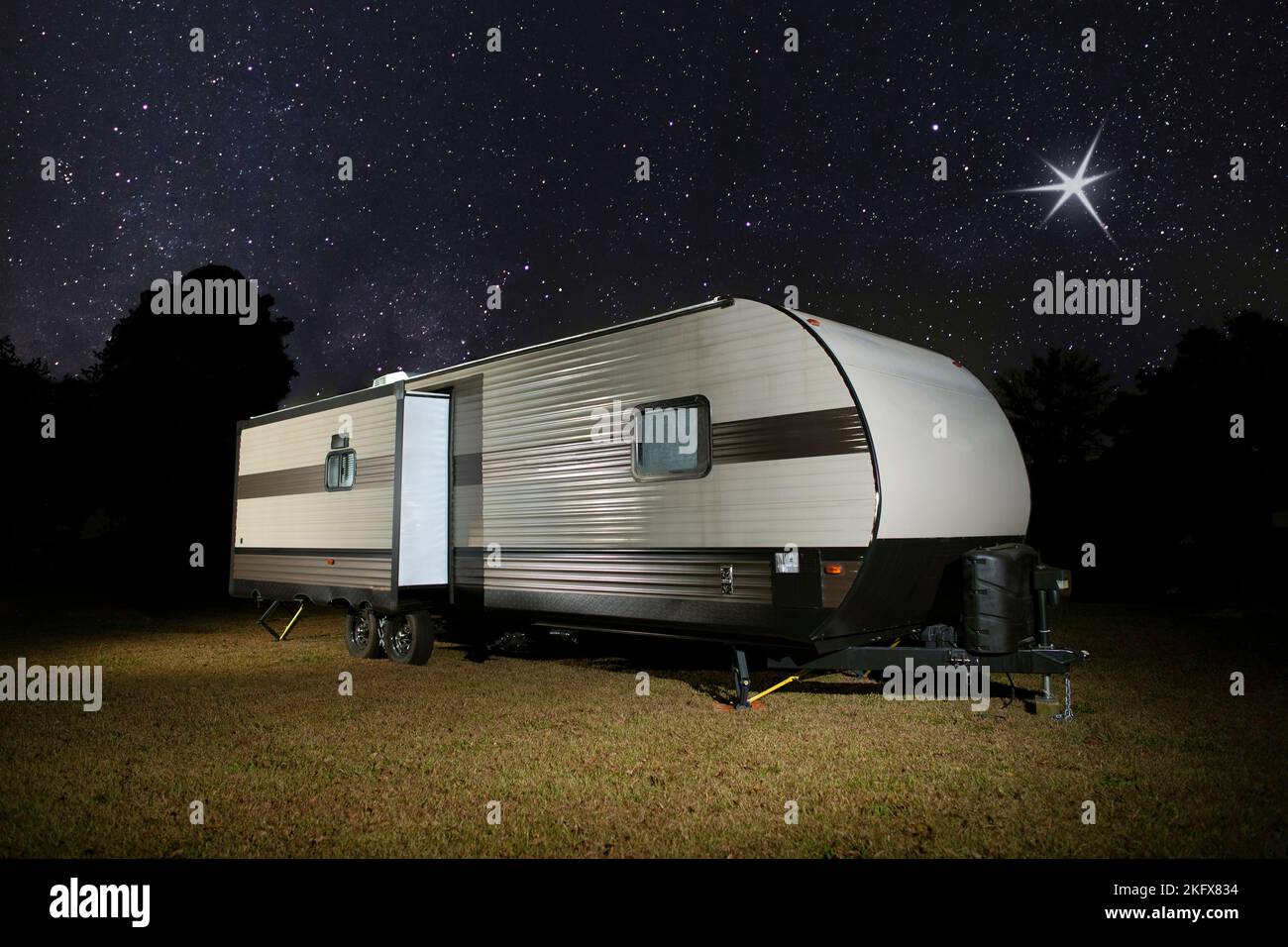 Camper su un punto erboso con stelle luminose sopra Foto Stock