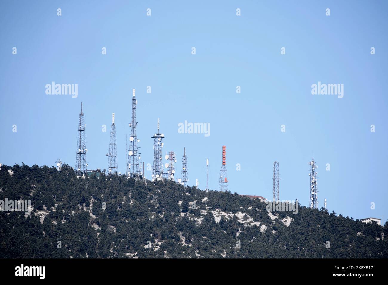 Antenne per telecomunicazioni sul monte Parnitha con alberi e cielo blu Foto Stock