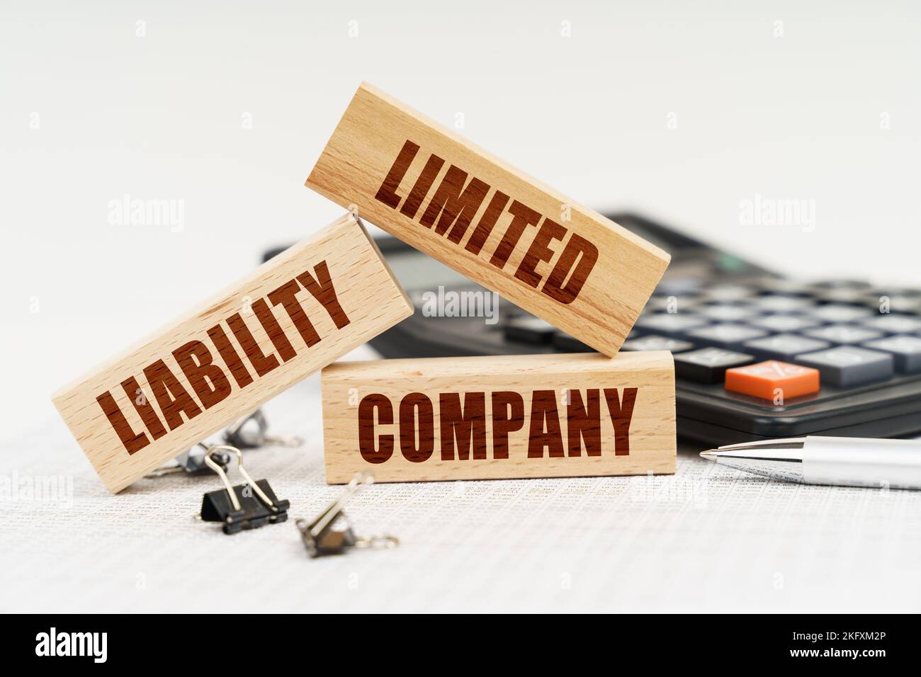 Business ed Economia. Sul tavolo c'è una penna, una calcolatrice e piccoli blocchi di legno con l'iscrizione - SOCIETÀ A RESPONSABILITÀ LIMITATA Foto Stock