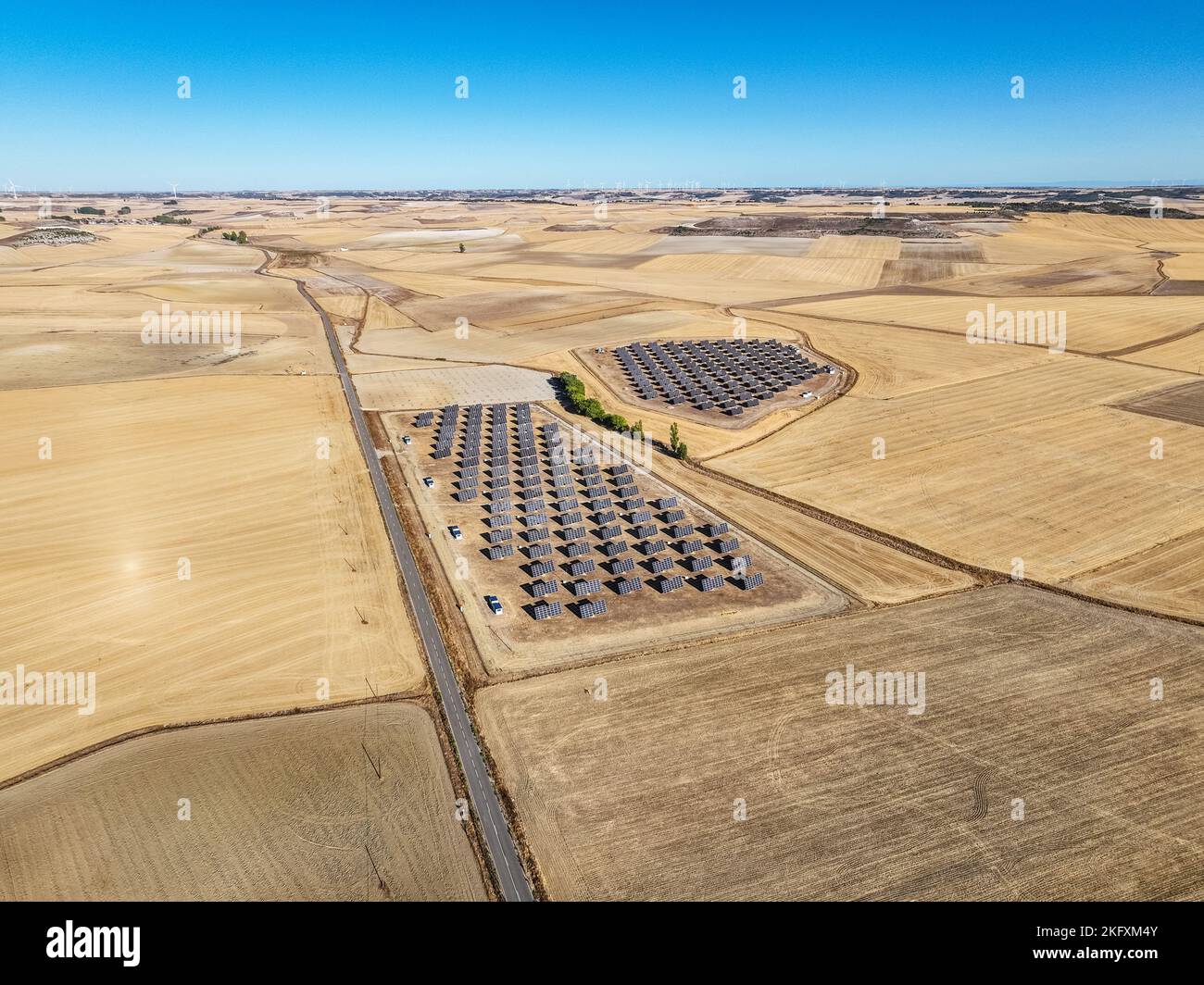 Vista aerea di una centrale fotovoltaica nella campagna al di fuori di Valladolid in Spagna, con alcuni mulini a vento sullo sfondo. Foto Stock