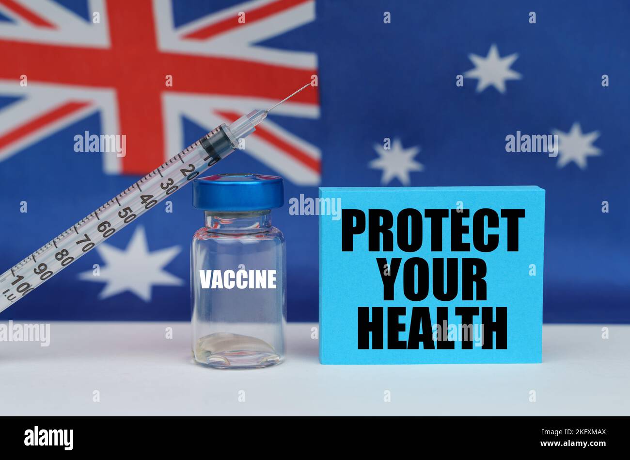 Concetto di medicina. Vaccino, siringa e piastra blu con l'iscrizione - PROTEGGERE LA SALUTE. Sullo sfondo la bandiera dell'Australia Foto Stock