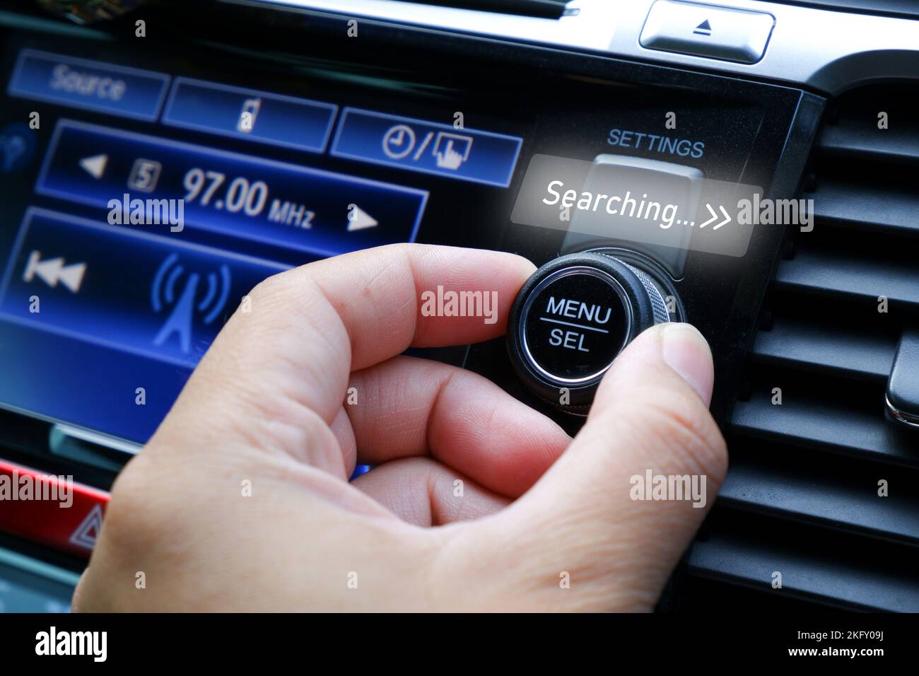 Il conducente regola la mano per cercare una stazione radio sul cruscotto dell'autoradio Foto Stock