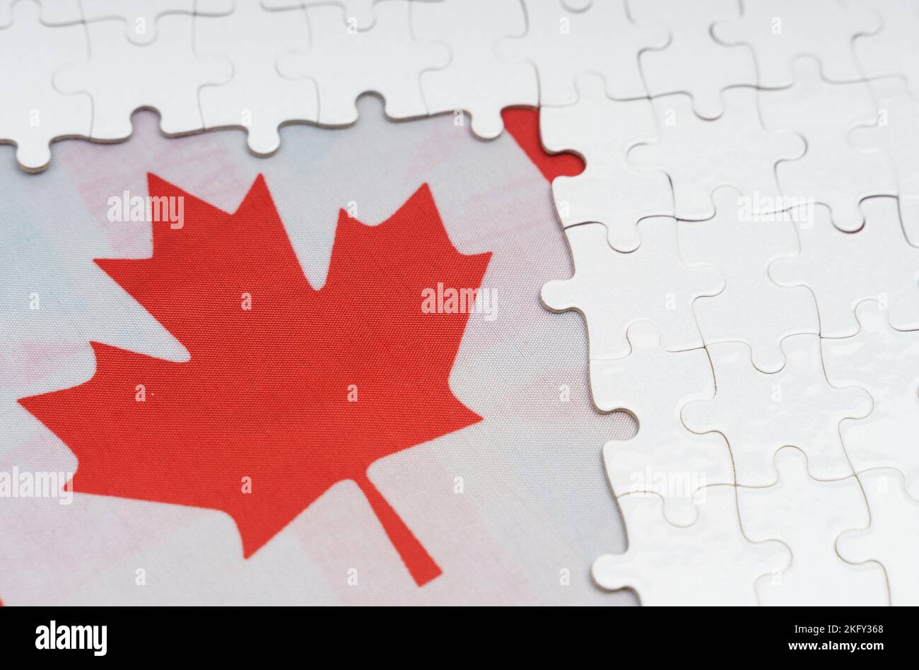 Concetto nazionale. Ci sono puzzle bianchi su un tavolo sopra la bandiera canadese. Foto Stock