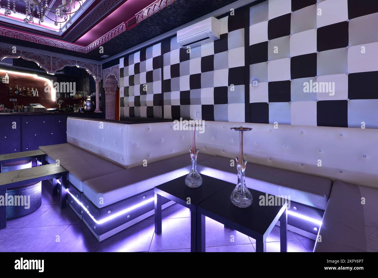 Lounge di un nightclub con posti a sedere continui imbottiti in skay bianco e luci al neon Foto Stock