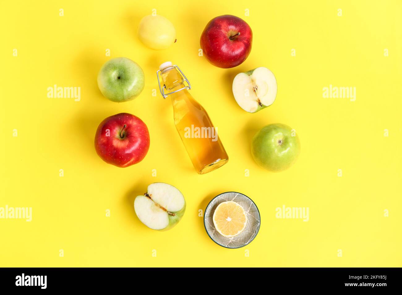 Composizione con bottiglia di aceto di sidro di mele e frutta su fondo giallo Foto Stock