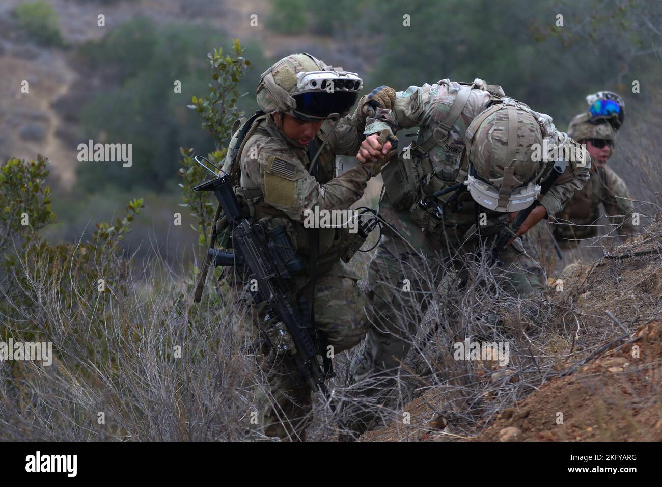 Soldati dell'esercito degli Stati Uniti assegnati a 5th squadrone, 73rd reggimento di cavalleria, 3rd squadra di combattimento di Brigade, 82nd divisione aerea, si aiutano a vicenda su una collina il 14 ottobre 2022, durante la sperimentazione di Project Convergence 22 (PC22) a Camp Talega, California. Nel corso del PC22 molti sistemi saranno sperimentati per determinare come le future capacità di comando e controllo possano essere integrate con i partner all-service e multinazionali. Foto Stock