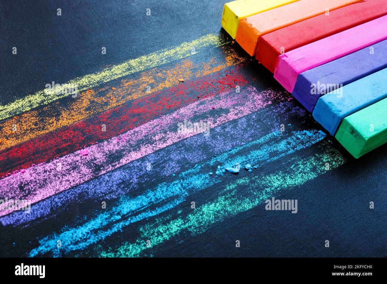 Pastelli multicolore su una lavagna nera come simbolo della creatività. Sfondo colorato. Foto Stock