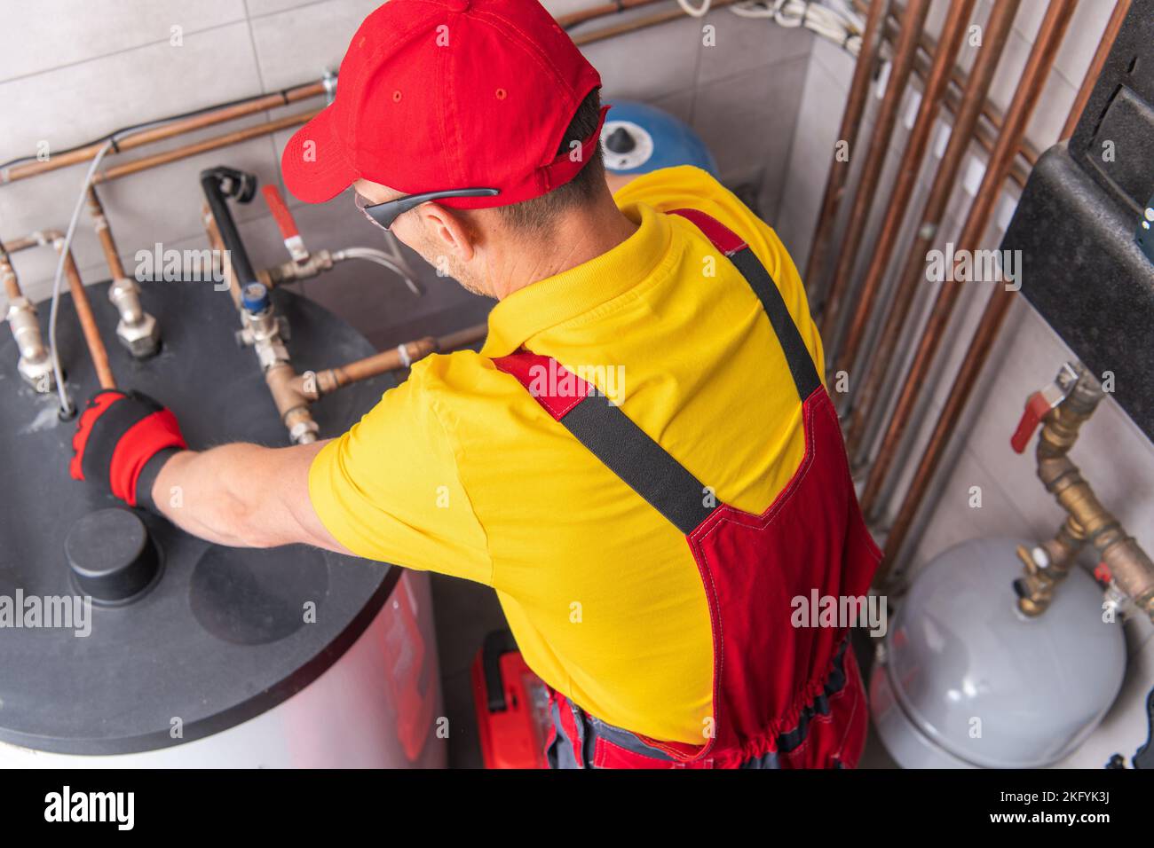 Serbatoio professionale per la riparazione di idraulici caucasici riscaldatore dell'acqua nel locale caldaie dell'edificio commerciale. Tema di manutenzione dell'attrezzatura di riscaldamento. Foto Stock