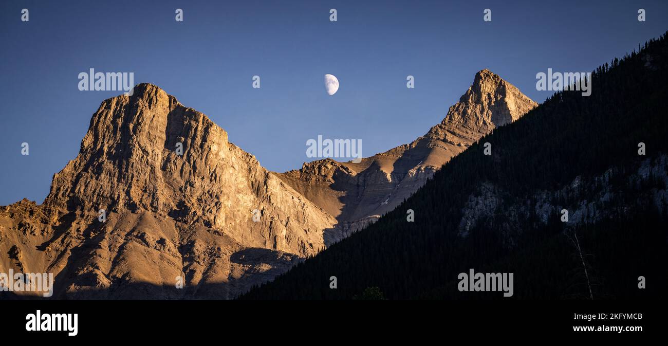 Vette rocciose con la luna in primo piano in serata. Foto Stock