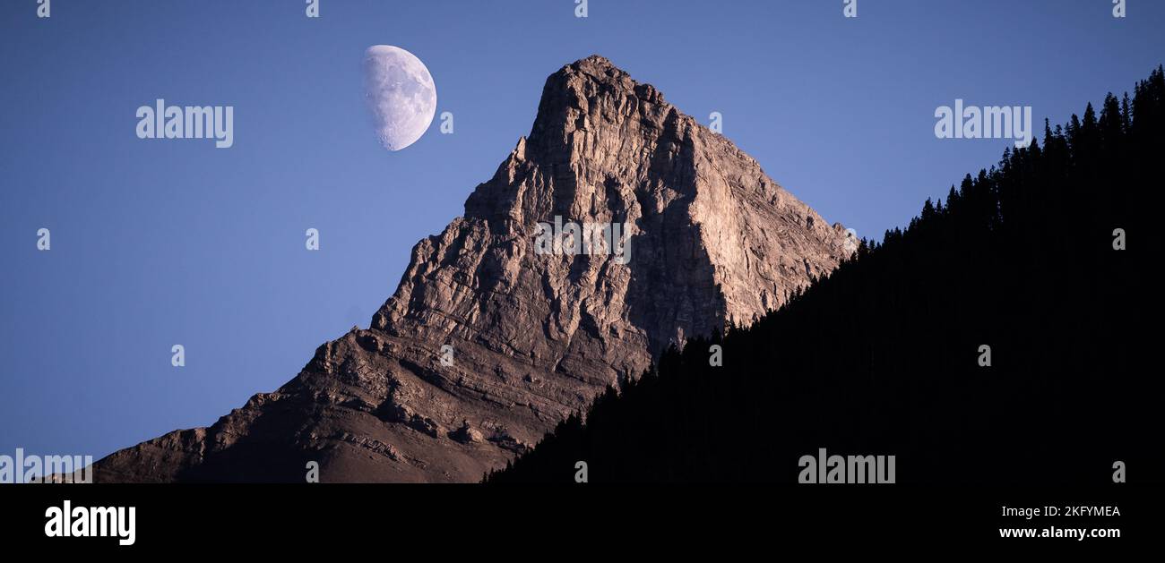 Vette rocciose con la luna in primo piano in serata. Foto Stock