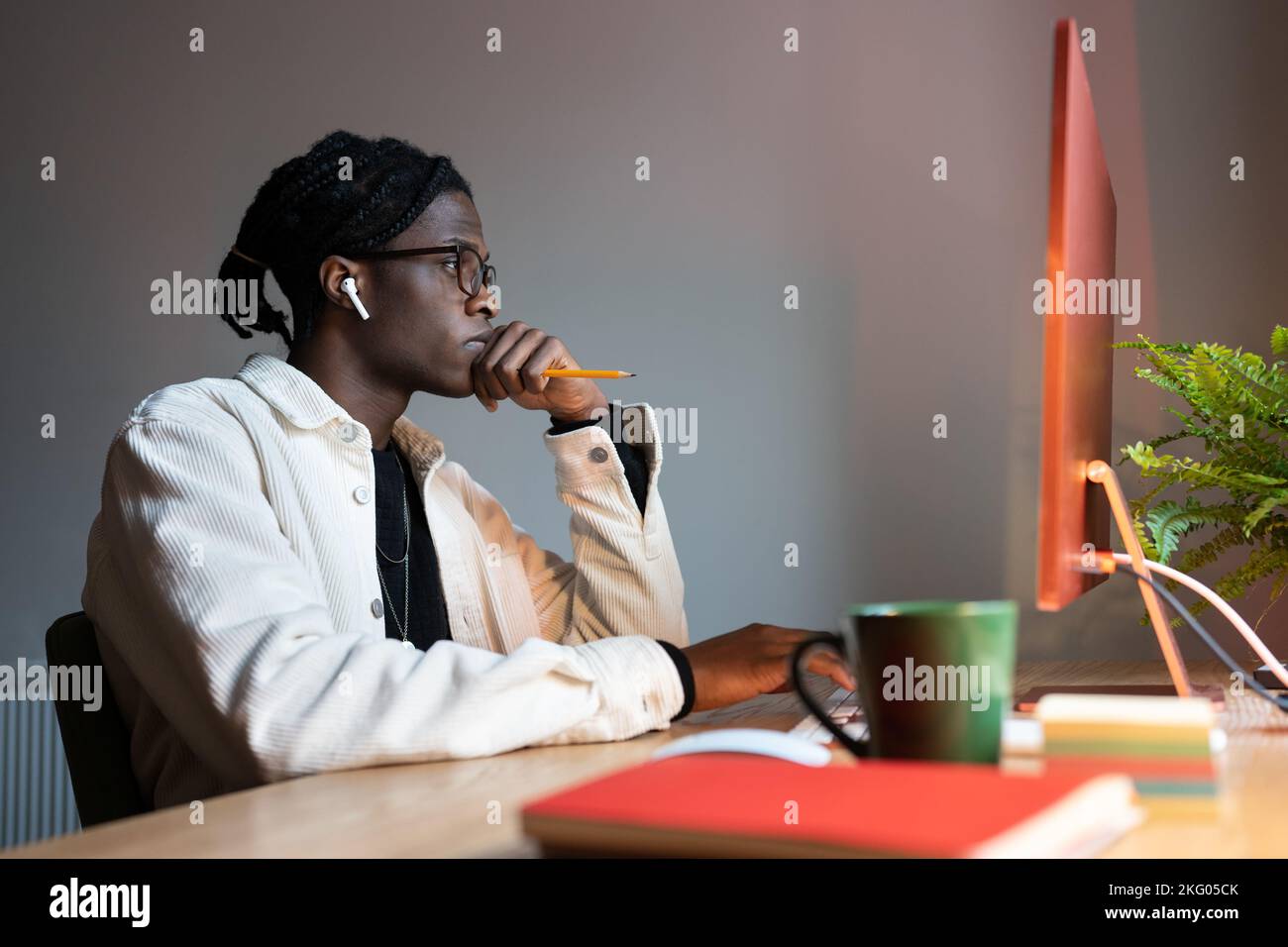 Il computer concentrato di successo dell'uomo afro-americano si siede sul posto di lavoro con la tazza di caffè Foto Stock