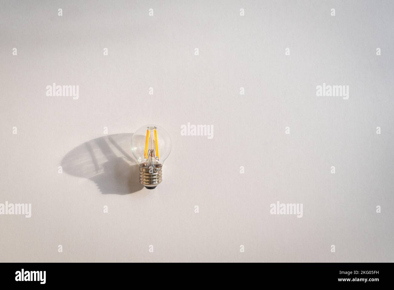 Lampadina e ombra sullo sfondo bianco della lavagna. Spazio di copia. Creatività, idee o concetto di ispirazione. Foto Stock