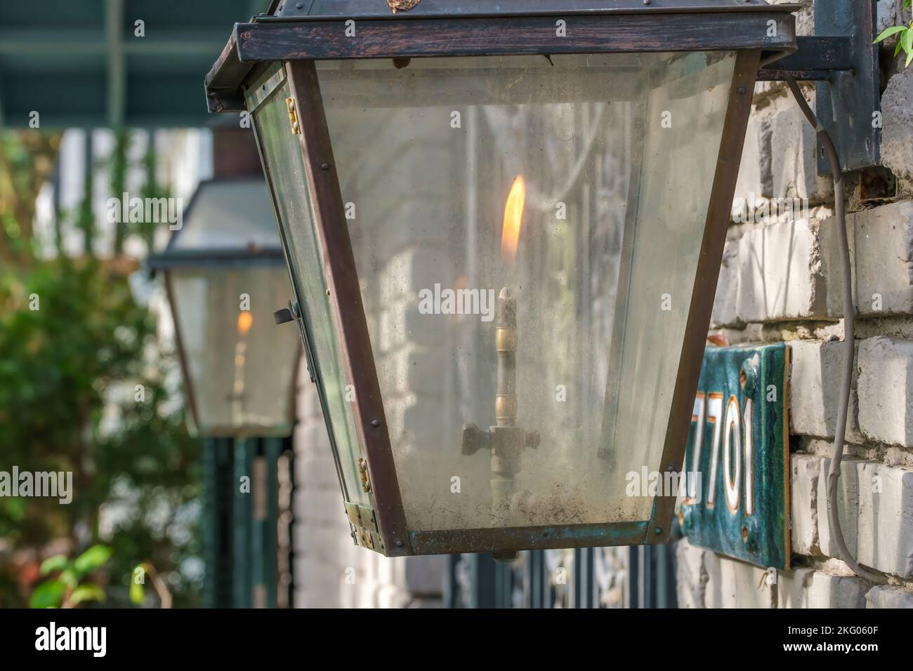 Primo piano di una lampada a gas vintage illuminata, con vetro molto sporco, davanti a una casa storica a New Orleans, Louisiana, USA Foto Stock