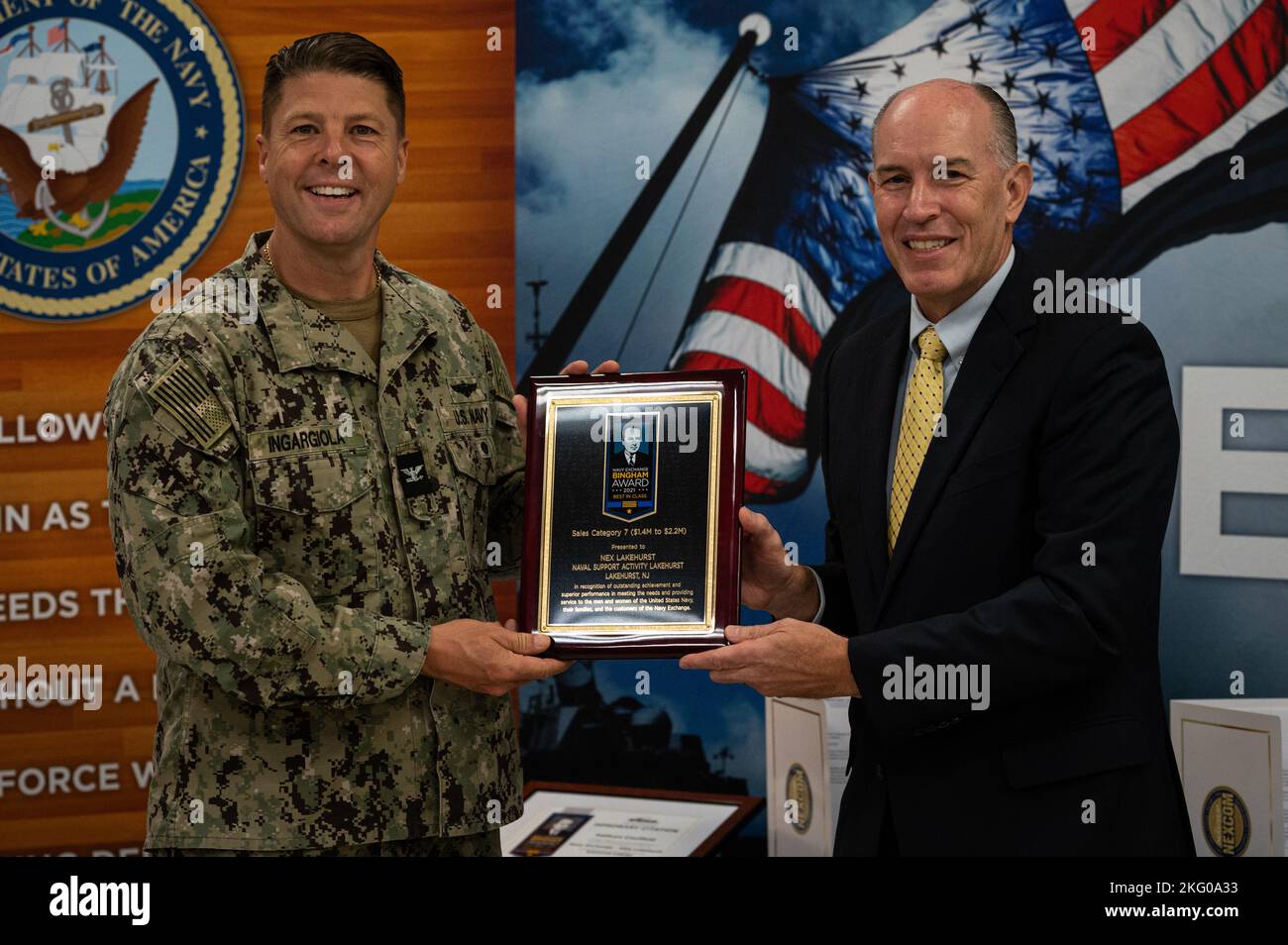 Christopher Burns, Senior Vice president del Navy Exchange Service Command, presenta il capitano della Marina statunitense Frank T. Ingargiola, vice comandante della Joint base McGuire-Dix-Lakehurst e comandante della Naval Support Activity Lakehurst, il Bingham Award 2021 alla Joint base MDL, N.J., 18 ottobre 2022. Navy Exchange Lakehurst ha ricevuto il premio per le vendite di oltre $1,4 a $2,2 milioni di euro. Il premio viene assegnato ai migliori NEX in nove categorie di vendita per i risultati finanziari complessivi e il servizio clienti. Foto Stock