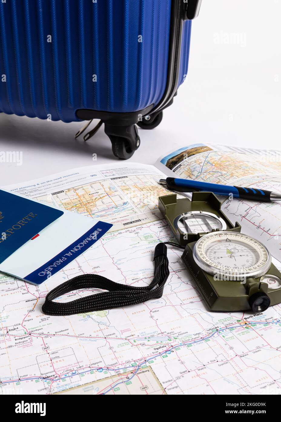 Accanto alle mappe, alla bussola e alla penna viene visualizzata una valigetta da viaggio blu, il tutto su sfondo bianco Foto Stock