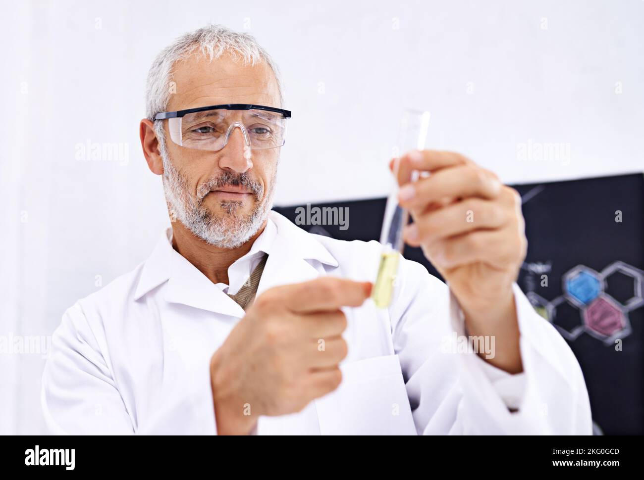 HES sta facendo alcune ricerche importanti al momento. Uno scienziato maschio maturo che esamina il contenuto di una provetta nel suo laboratorio. Foto Stock