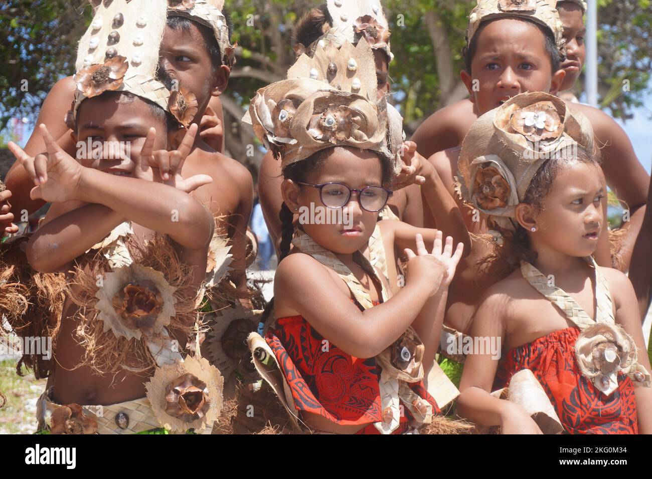 Primo piano di un piccolo gruppo di bambini polinesiani vestiti tradizionalmente con una ragazza che indossa gli occhiali Foto Stock