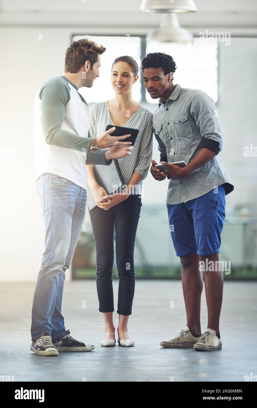 Lascia passare con alcune idee. Foto a tutta lunghezza di tre giovani designer che parlano in ufficio. Foto Stock