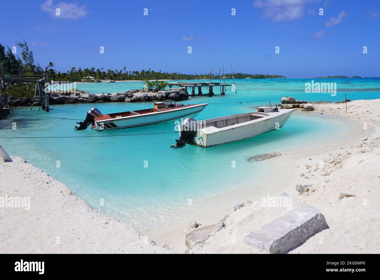 Idilliaco atollo polinesiano con barche e acque turchesi Foto Stock