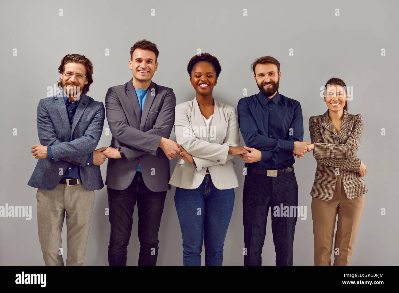 Ritratto di un gruppo sorridente di diverse persone d'affari multirazziali in piedi in una fila tenendo le mani. Foto Stock