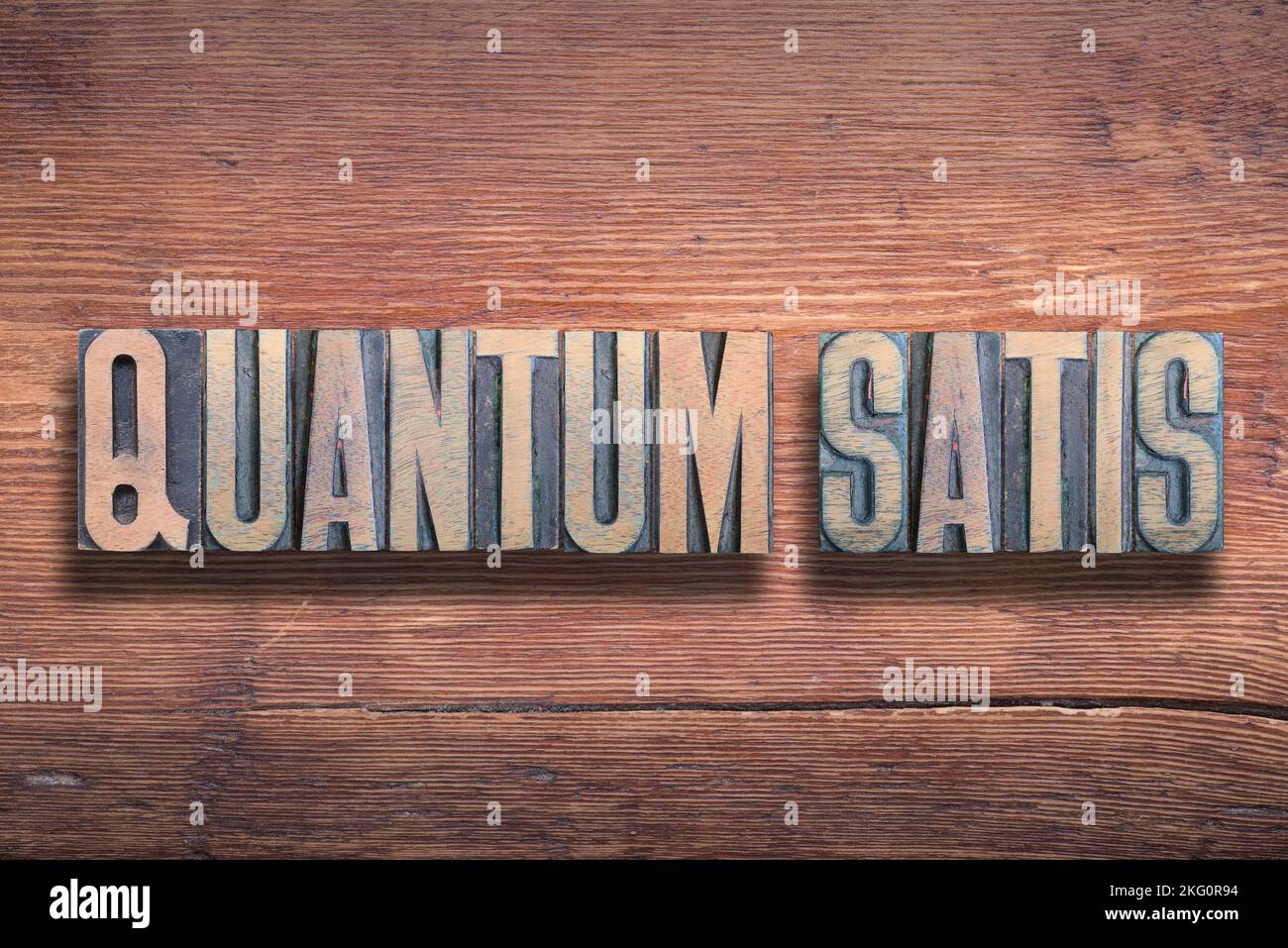 Quantum Satis (quanto necessario, abbastanza) frase latina combinata su superficie di legno laccato vintage Foto Stock
