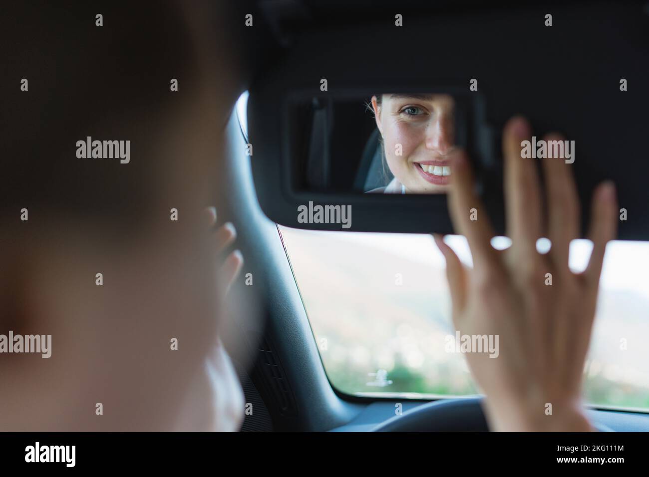 Vista posteriore della giovane donna in auto, guardando lo specchietto retrovisore. Foto Stock