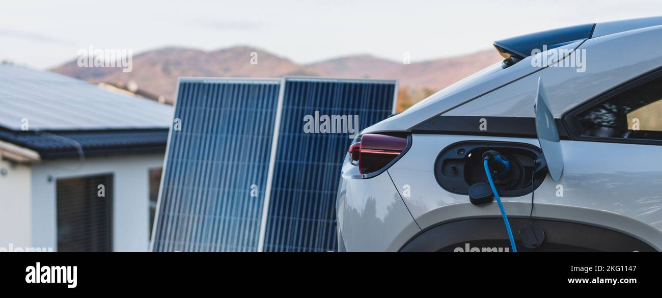 Caricare un'auto elettrica da casa centrale fotovoltaica, concetto di trasporto sostenibile ed economico. Foto Stock