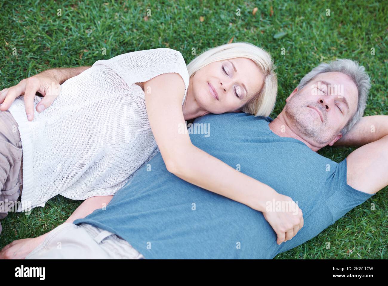 Intimità e beatitudine. Una coppia matura distesa sull'erba e che ti guarda felicemente. Foto Stock