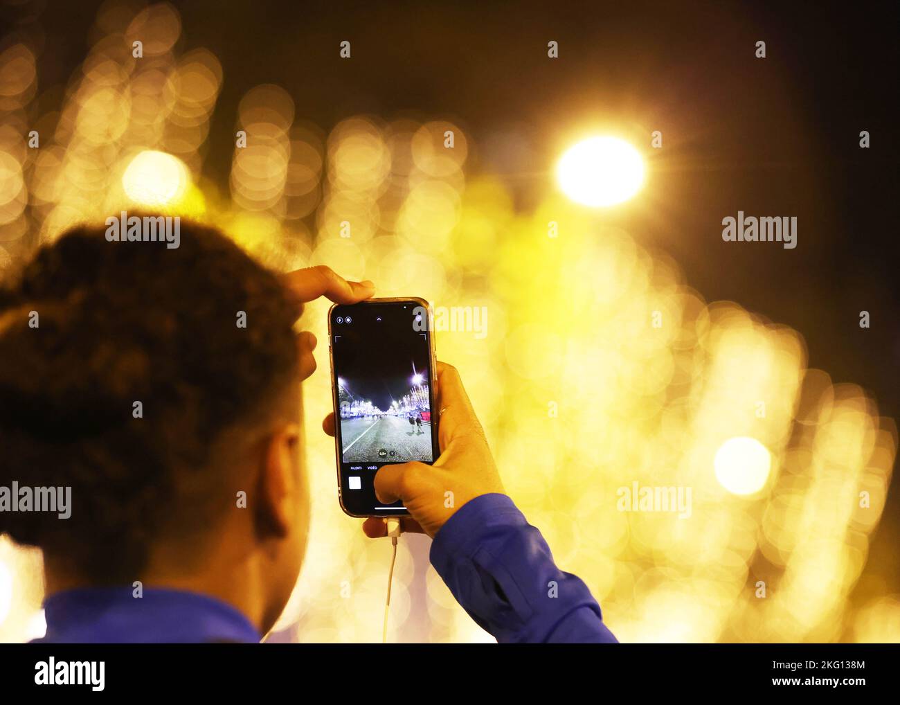 Parigi, Francia. 20th Nov 2022. Un uomo scatta foto agli Champs-Elysees illuminati dalle luci natalizie a Parigi, Francia, 20 novembre 2022. La cerimonia annuale di illuminazione di Natale si è tenuta qui domenica. Le luci sul famoso viale saranno spente all'ora precedente delle 11:45 invece delle 2:00 e dureranno fino al 2 gennaio 2023, una settimana prima del solito per risparmiare energia. Credit: Gao Jing/Xinhua/Alamy Live News Foto Stock