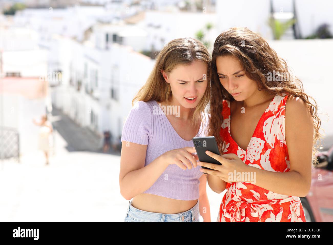 Due turisti preoccupati che controllano le notizie in linea dello smartphone sulle vacanze estive Foto Stock