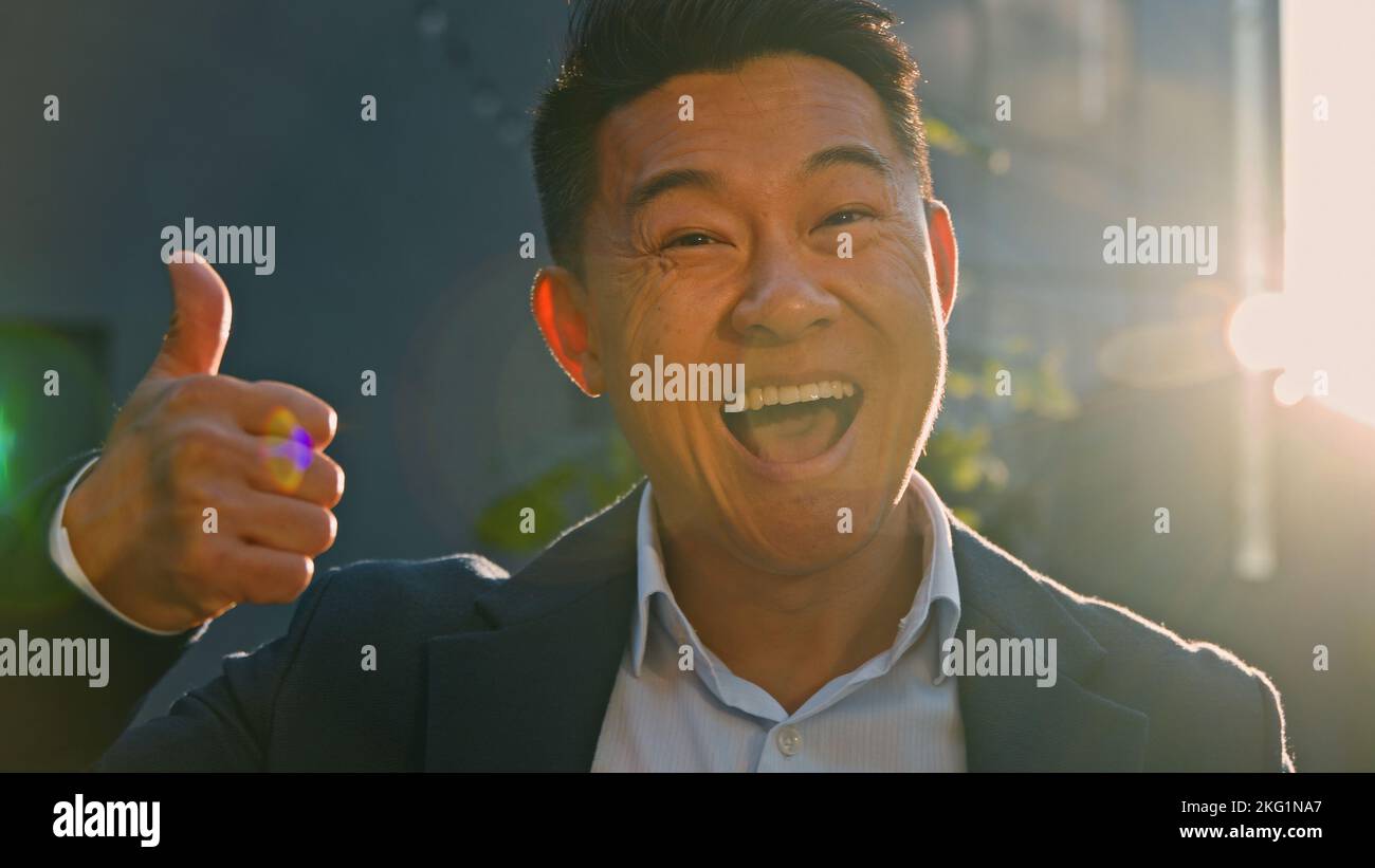 Ritratto felice sorridente toothy soddisfatto riuscito felice asiatico 40s uomo di mezza età capo leader uomo d'affari in piedi all'aperto in luci di sole in raggi di sole Foto Stock