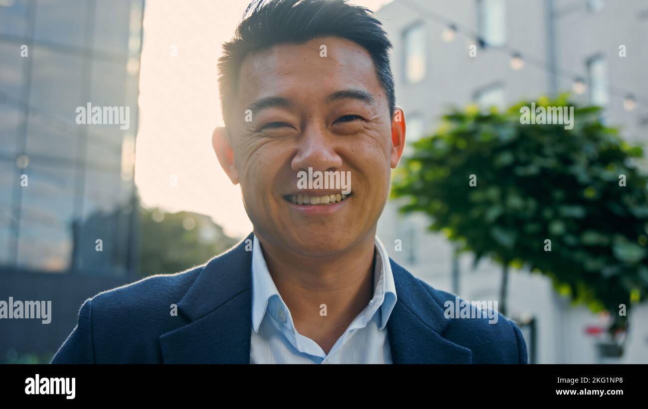Uomo d'affari asiatico felice uomo d'affari di mezza età che ride sincero all'aperto in città emotivamente ridere sorriso con scherzo situazione divertente divertirsi Foto Stock