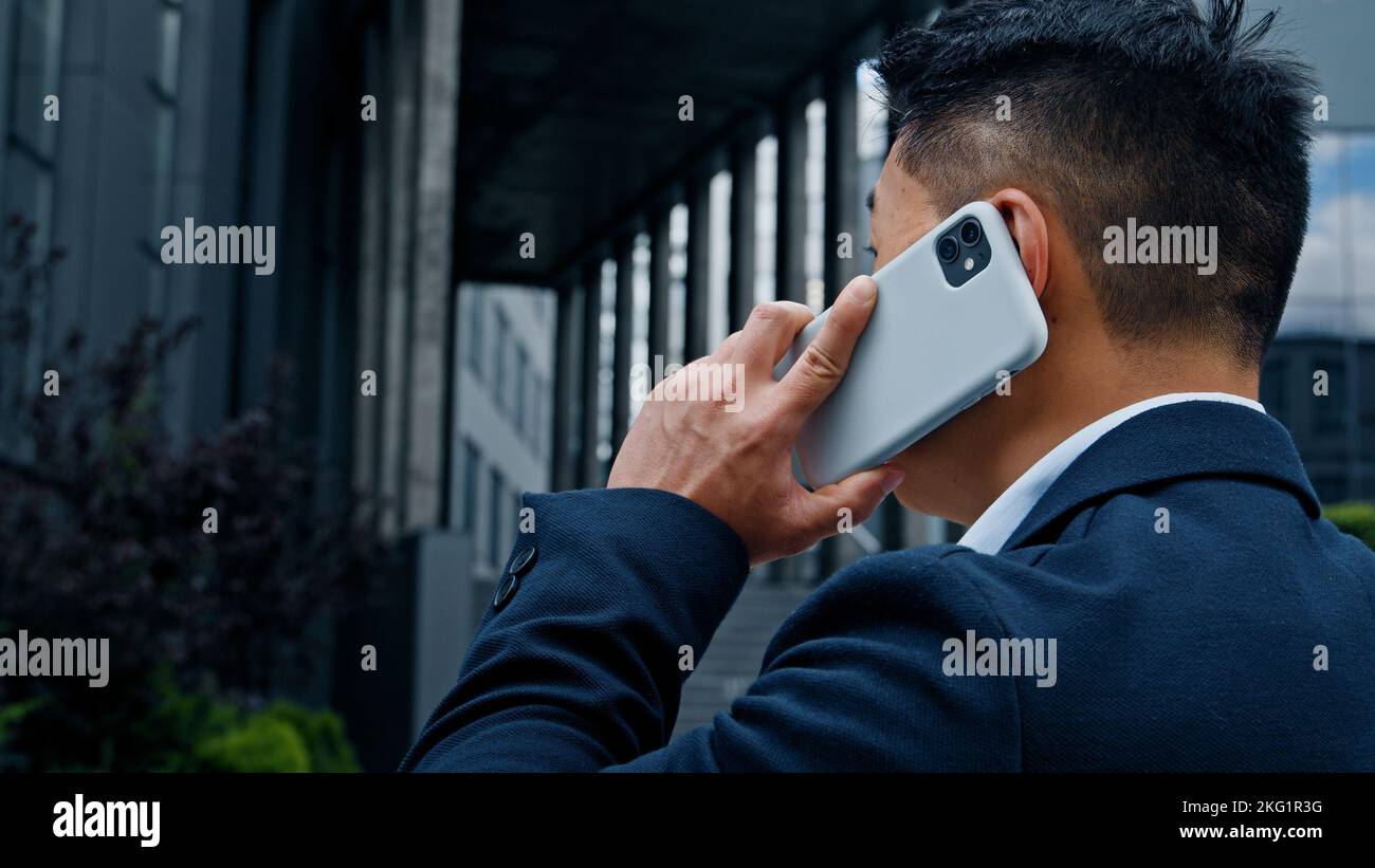 Vista posteriore uomo d'affari asiatico di mezza età CEO datore di lavoro imprenditore capo manager formale uomo ha conversazione cellulare con smartphone Foto Stock
