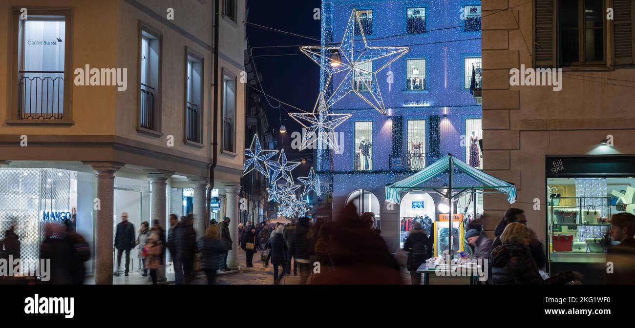 Varese, Italia. Strada di notte illuminata con decorazioni natalizie e folla di persone per lo shopping natalizio. Centro storico, corso Matteotti Foto Stock