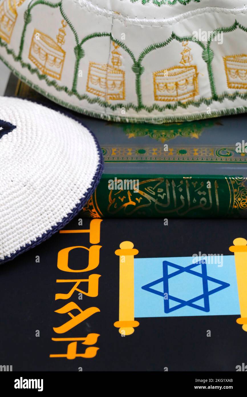 Simboli religiosi : cappello musulmano di Kufi con il Corano, e Kippah ebraico con la Torah. Concetto di dialogo interreligioso o interreligioso. Foto Stock