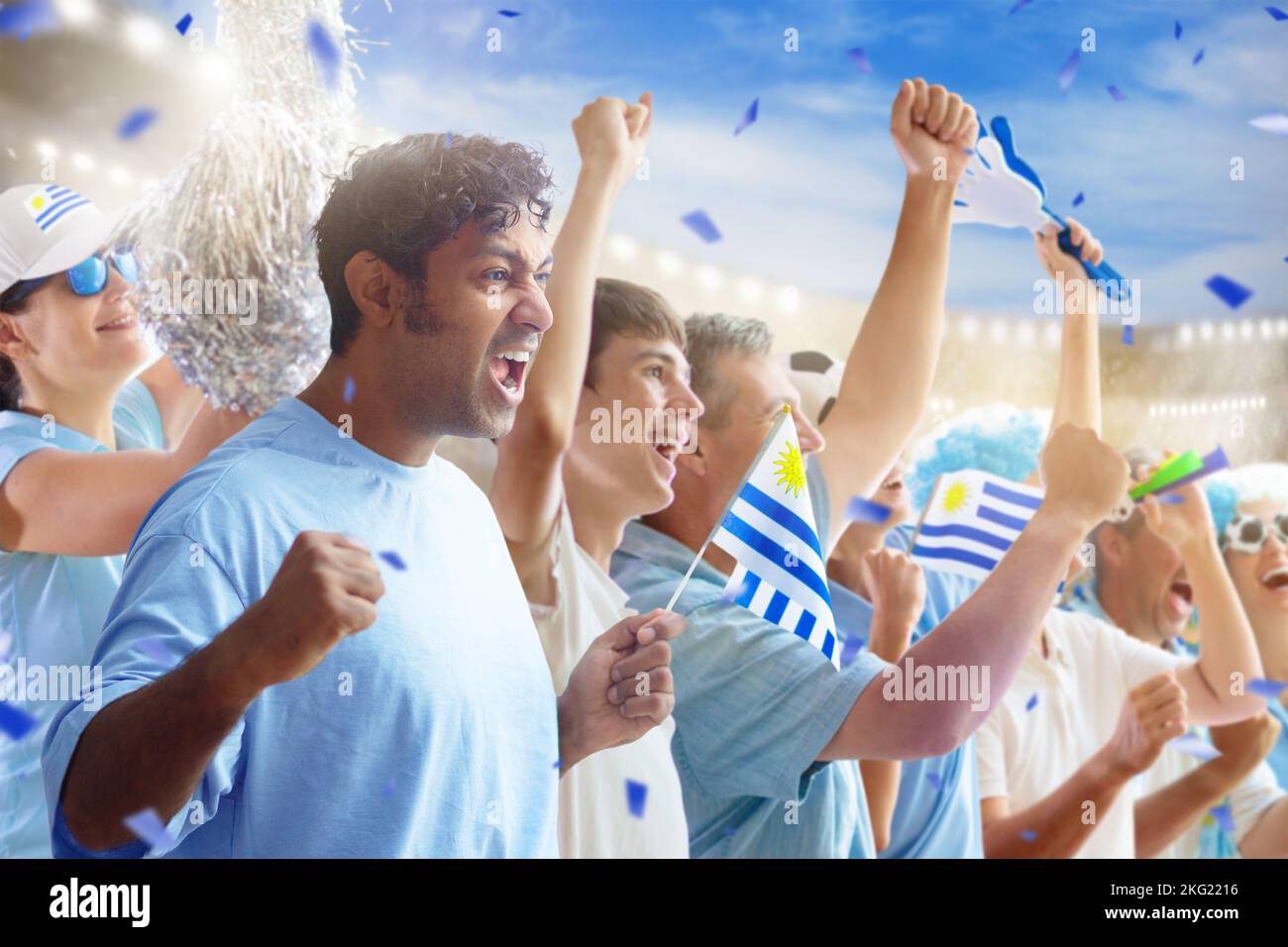 Sostenitore del calcio dell'Uruguay nello stadio. Tifosi uruguaiani sul campo da calcio guardando gioco di squadra. Gruppo di tifosi con bandiera e maglia nazionale Foto Stock