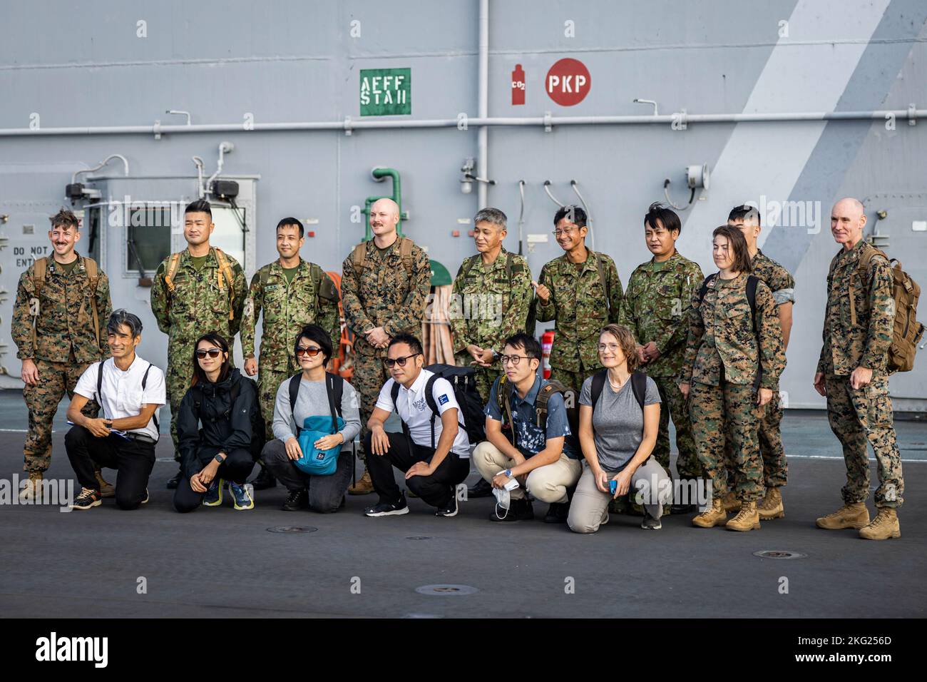 I Marines degli Stati Uniti, membri della forza di autodifesa di terra del Giappone e i reporter giapponesi locali posano per una foto di gruppo a bordo della USS Tripoli (LHA-7) mentre è portato nella spiaggia bianca della stazione navale, Okinawa, Giappone, 24 ottobre 2022. III Marine Expeditionary Force ha ospitato un seminario di media per i rappresentanti dei media di Okinawan per fornire una migliore comprensione di ciò che il III MEF fa al fine di migliorare le relazioni con la loro nazione ospitante. I rappresentanti dei media hanno avuto l'opportunità di volare su aerei militari, osservare le gamme di fuoco dal vivo e visitare il Jungle Warfare Training Center. Foto Stock