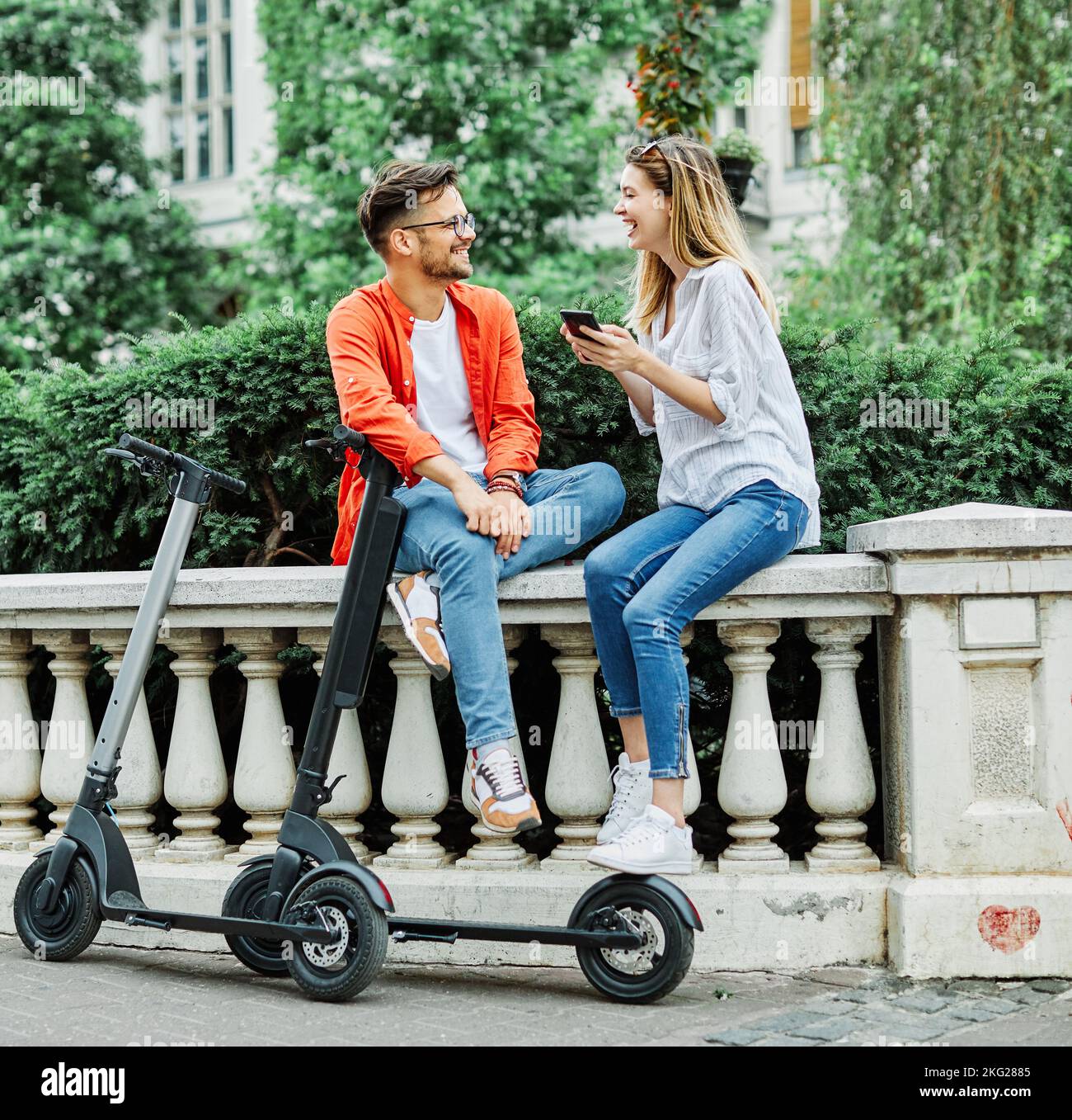 coppia giovane scooter elettrico città trasporto equitazione tecnologia lifestylestreet amico guida moderno Foto Stock