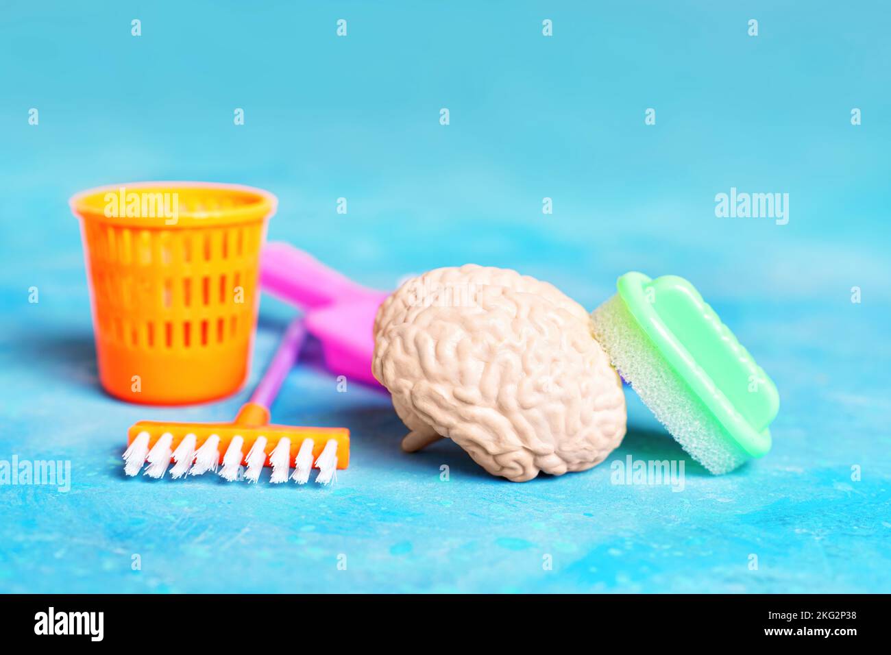 Cervello umano e giocattolo casa strumenti di pulizia disposti su sfondo blu. Concetto di pulizia profonda della mente. Foto Stock