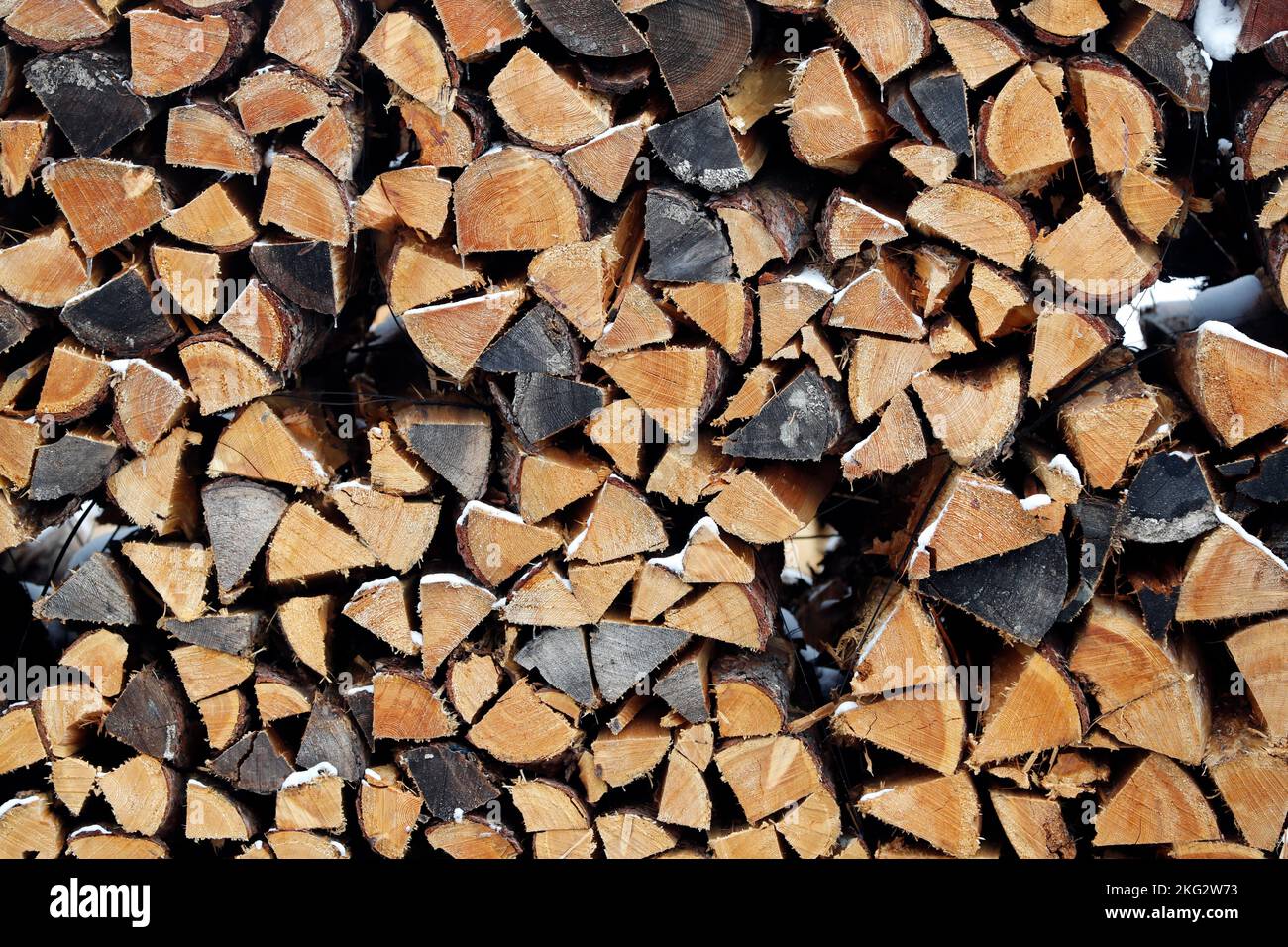 Pila di legna da fuoco con tronchi spaccati sotto la neve d'inverno. Svizzera. Foto Stock