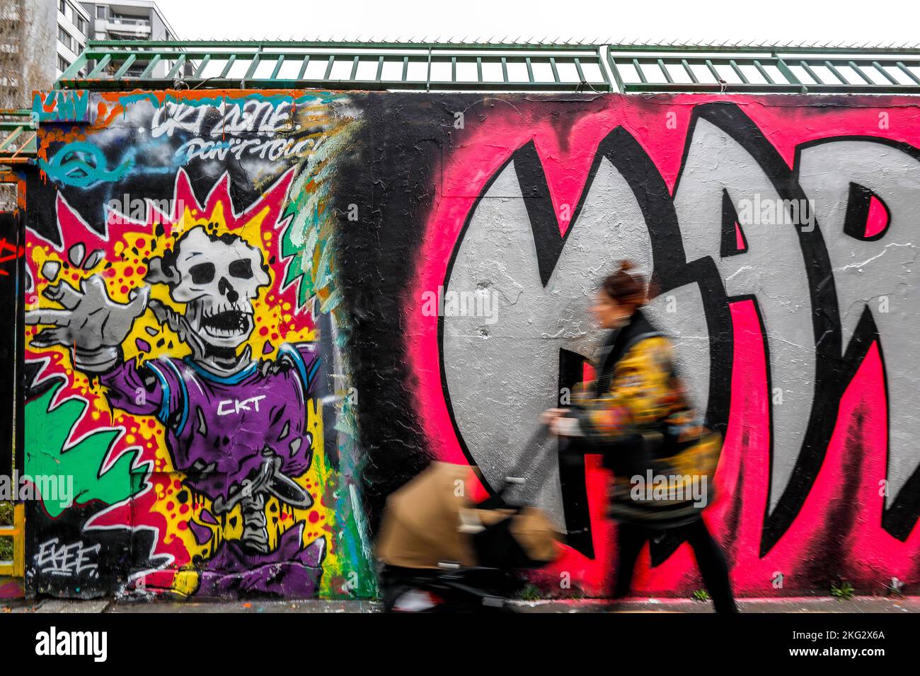 Donna che passa davanti a un muro con arte di strada a Parigi, Francia Foto Stock