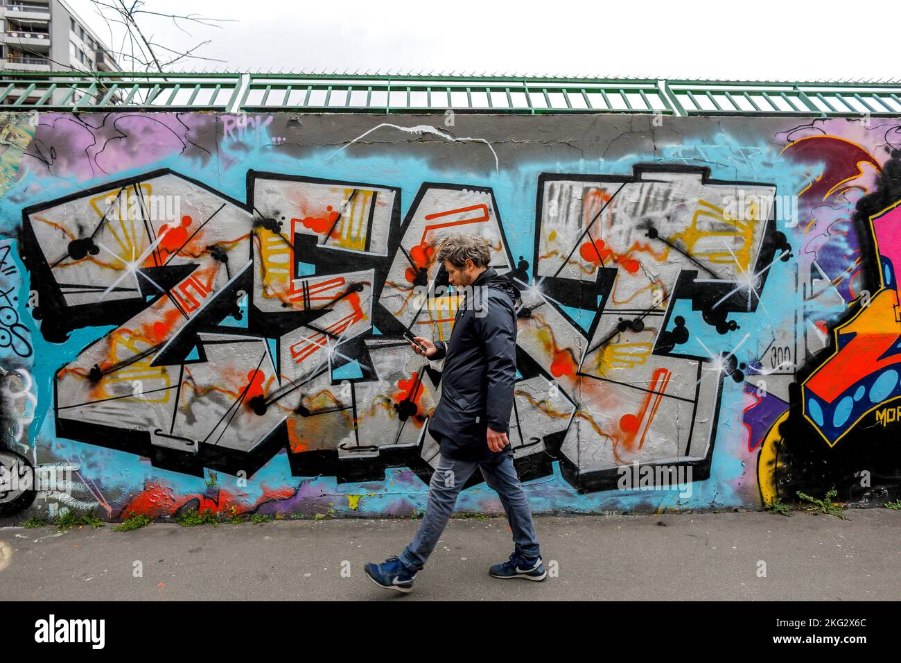 Uomo che cammina davanti a un muro con Street art a Parigi, Francia Foto Stock