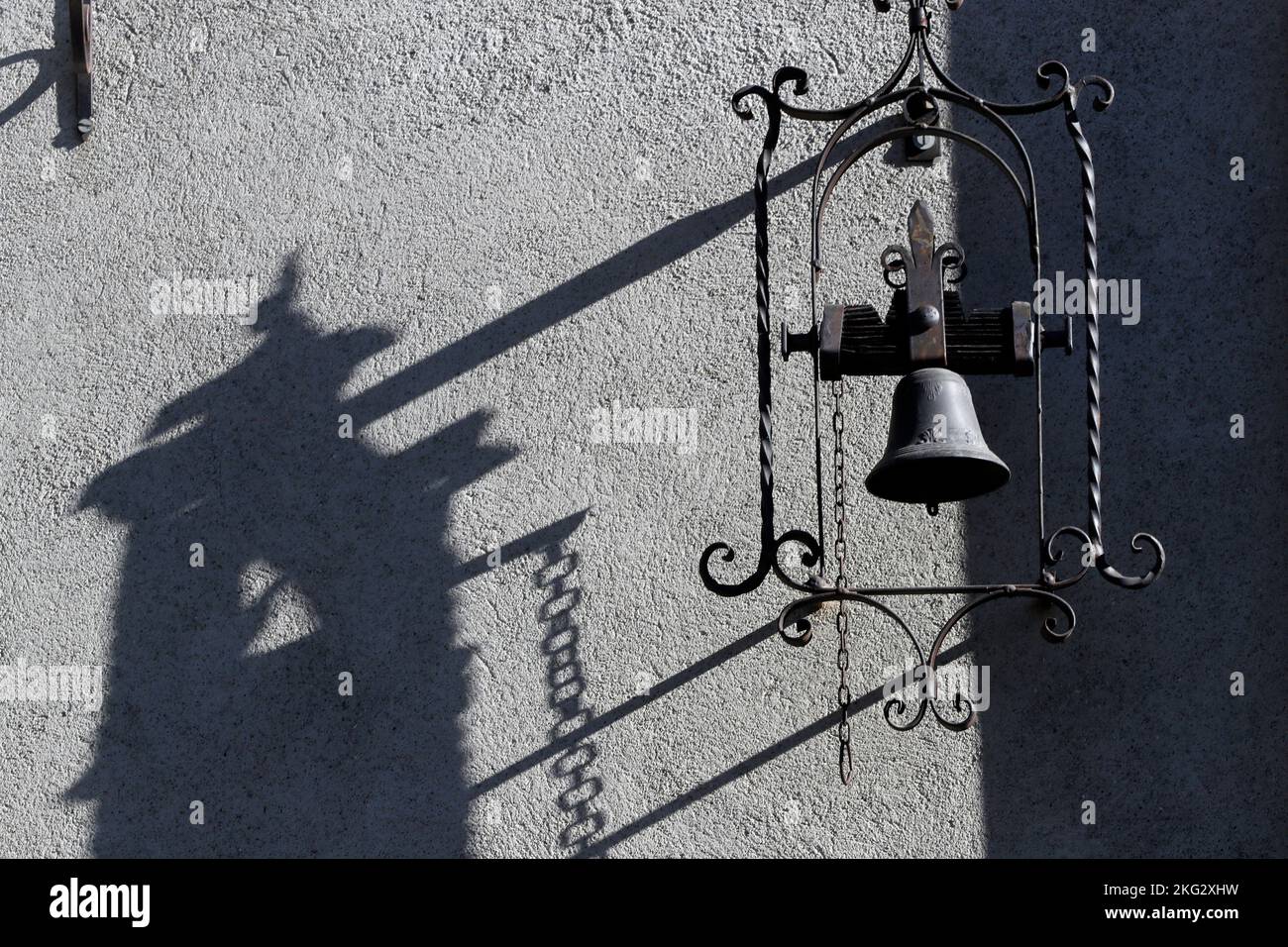 Ombra di una vecchia campana di metallo su una parete bianca. Francia. Foto Stock