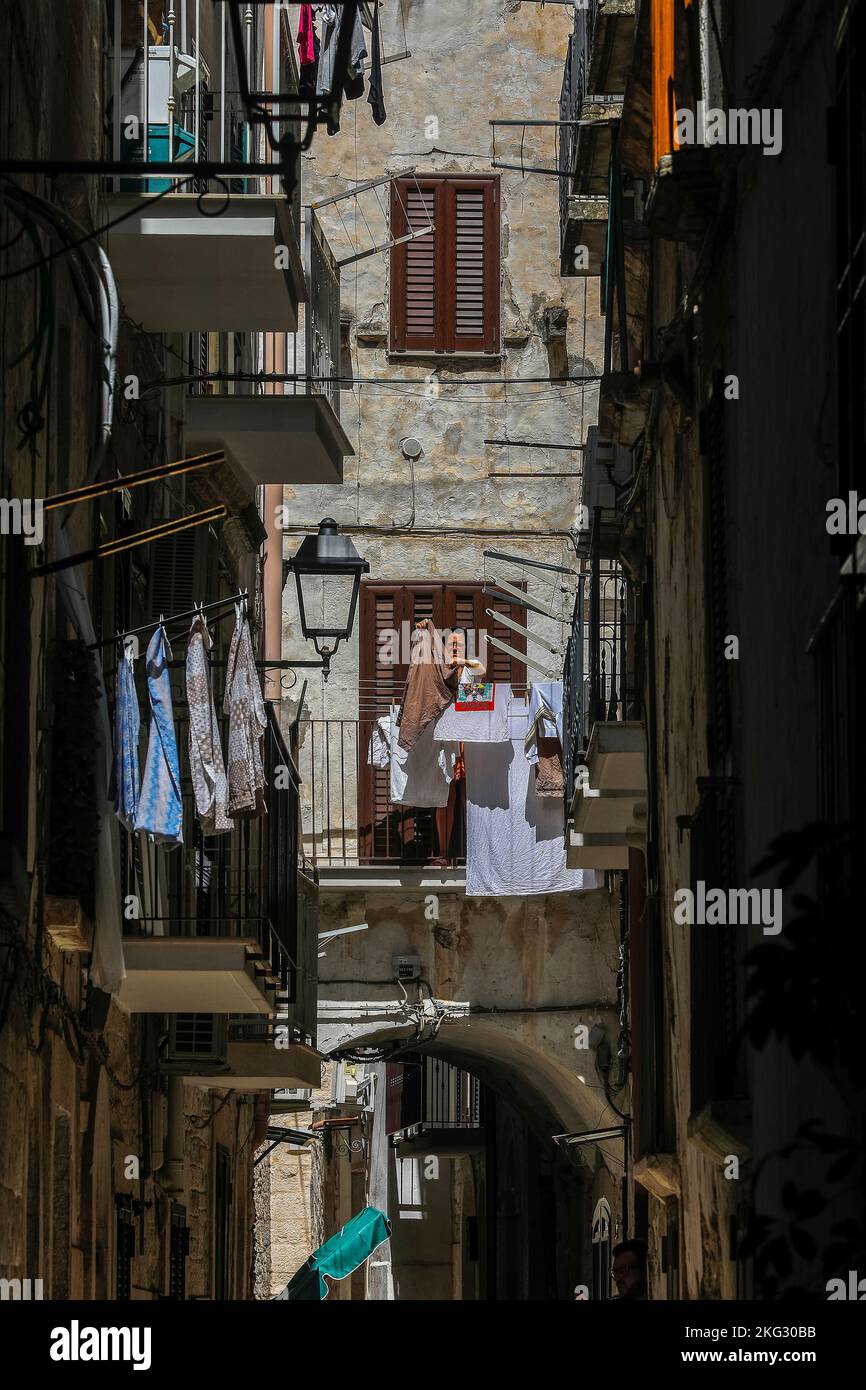 Donna che asciuga il bucato sul suo balcone a Bitonto, Puglia, Italia. Foto Stock