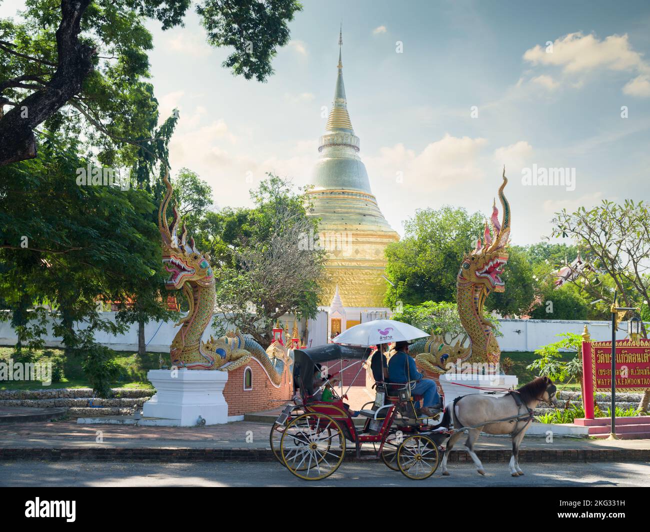 Lampang città, Thailandia. Novembre 21, 2022. Tempio Wat Kaew Don Tao Suchadaram. I turisti che cavalcano una tradizionale carrozza trainata da cavalli presso il tempio Foto Stock