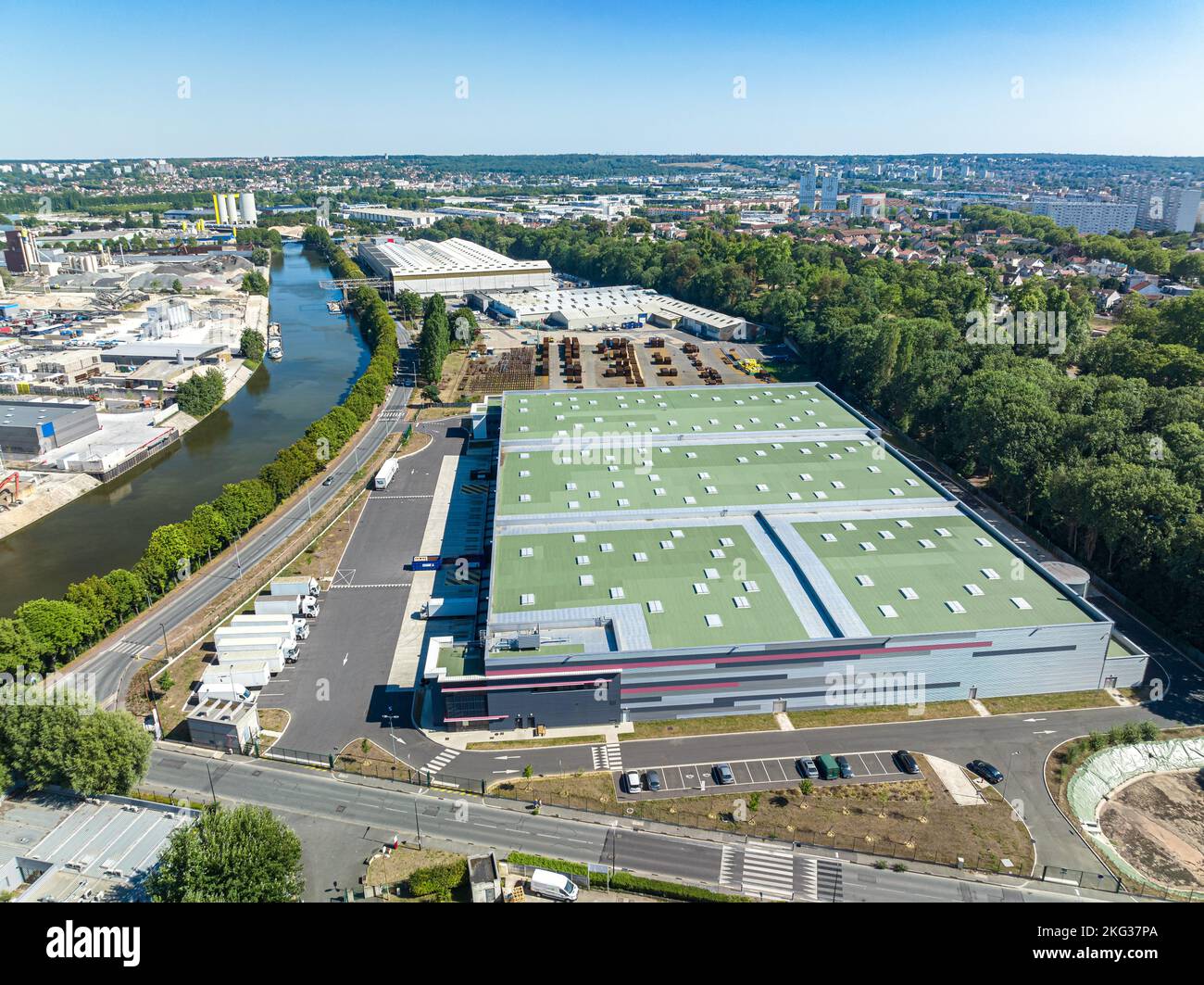 Drone shot di zona industriale con lago nel mezzo di molte infrastrutture commerciali e verde lussureggiante a Bonneuil sur Marne, Francia Foto Stock