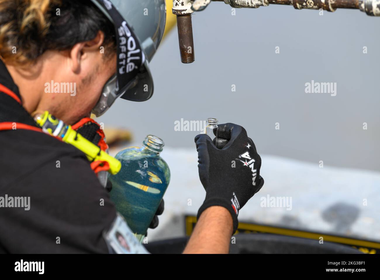 Naval Supply Systems Command Fleet Logistics Center dipendente di Pearl Harbor Lawsen Lee, addetto al sistema di distribuzione del carburante, osserva un campione di F76 di carburante diesel marino durante un'operazione di disimballaggio a bordo della Joint base Pearl Harbor-Hickam (JBPHH), Hawaii, 27 ottobre 2022. L'operazione di disimballaggio rimuoverà circa un milione di galloni di carburante dalle tre tubazioni del carburante principali che collegano l'impianto di stoccaggio del carburante alla rinfusa (RHBFSF) di Red Hill ai punti del carburante sul JBPHH. JTF-RH è stato istituito dal Dipartimento della Difesa per garantire la dealimentazione sicura e rapida del RHBFSF. Foto Stock
