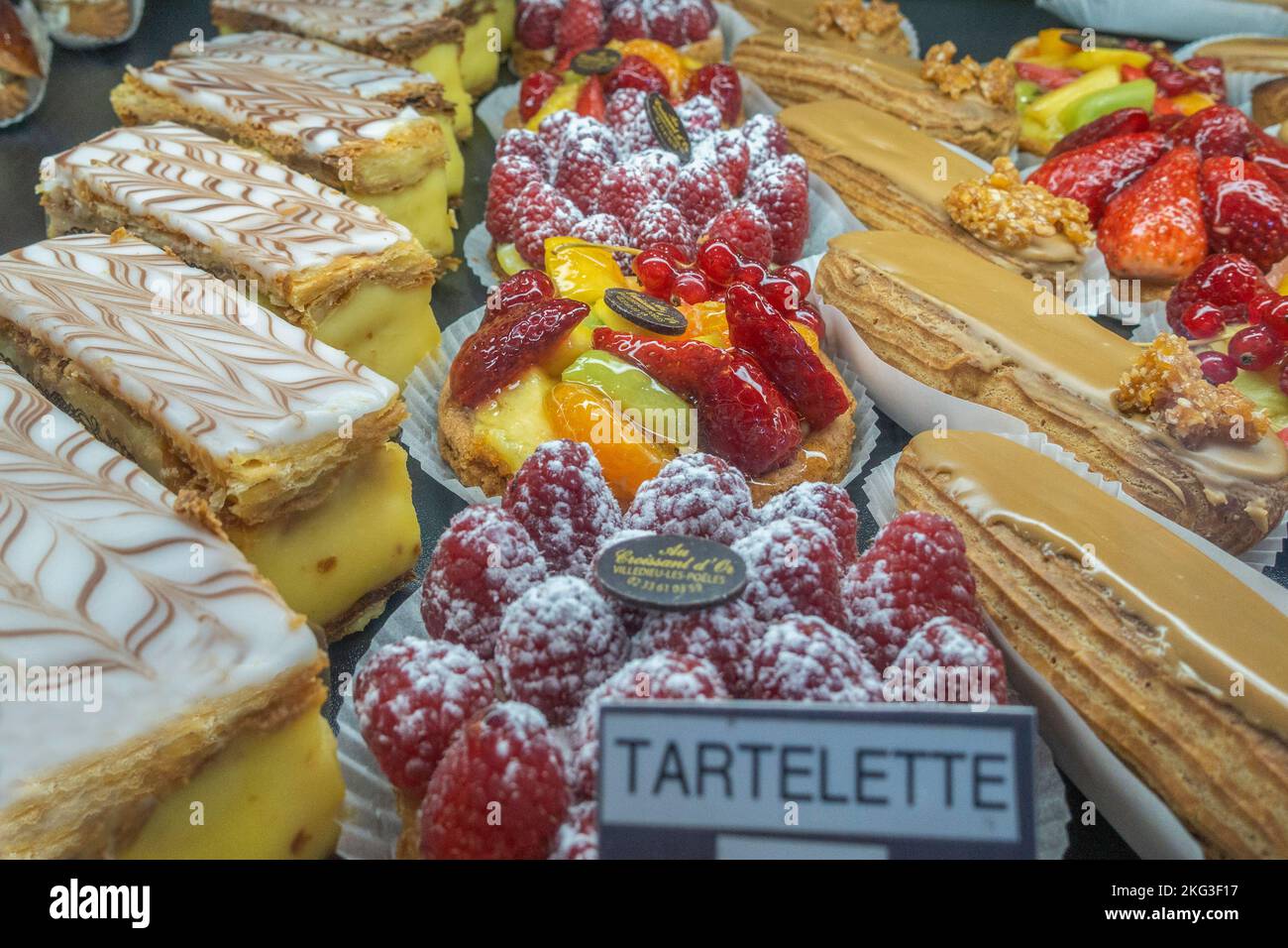 Pasticceria francese estremamente yummy in una vetrina in Francia tra cui eclairs, tartelettes aux Fruits e creme patissière ripieno di mille feuilles Foto Stock