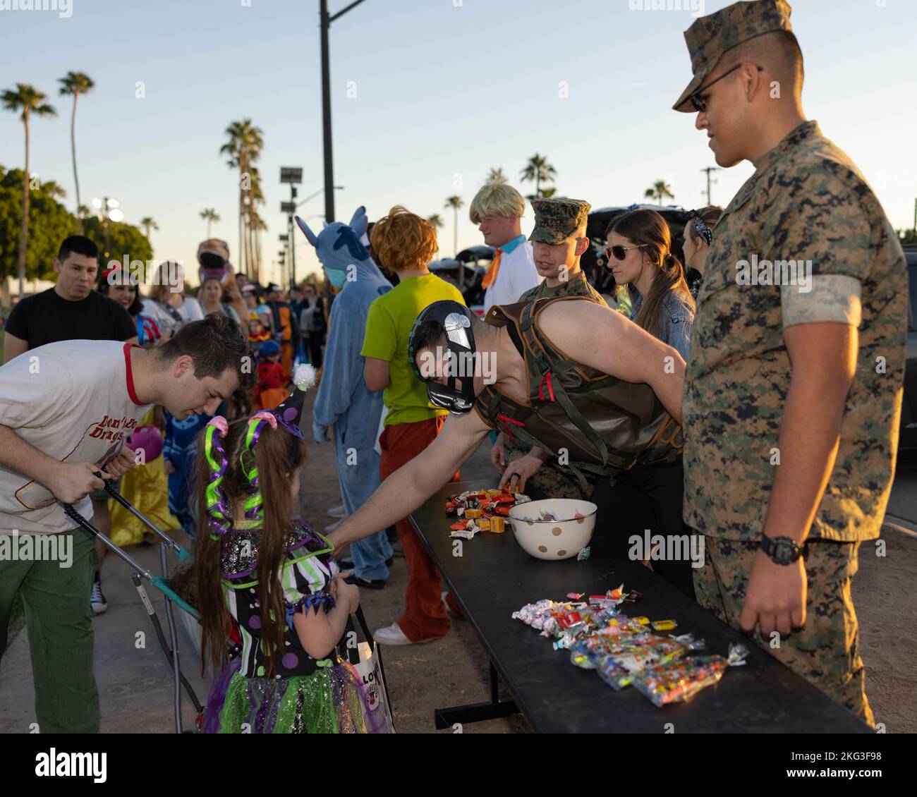 U.S. Marine Corps CPL. Patric Green, Center, Correction Specialist, Headquarters and Headquarters Squadron, Marine Corps Air Station (MCAS) Yuma, consegna caramelle ai bambini durante il 8th° anno Trunk or Treat a MCAS Yuma, Arizona, 27 ottobre 2022. Questo evento è stato ospitato dai Marine Corps Community Services e ha incoraggiato la partecipazione delle unità al fine di mantenere le relazioni con la comunità su MCAS Yuma. Foto Stock