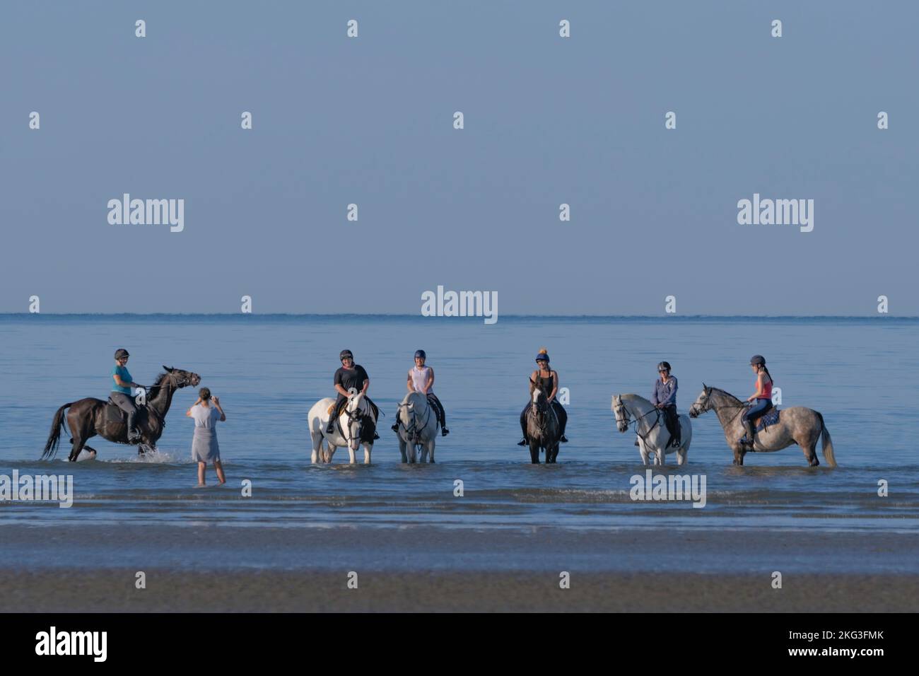 Un gruppo di cavalieri che hanno le loro foto scattate nelle acque calme della spiaggia di West Wittering nel Sussex occidentale. Foto Stock